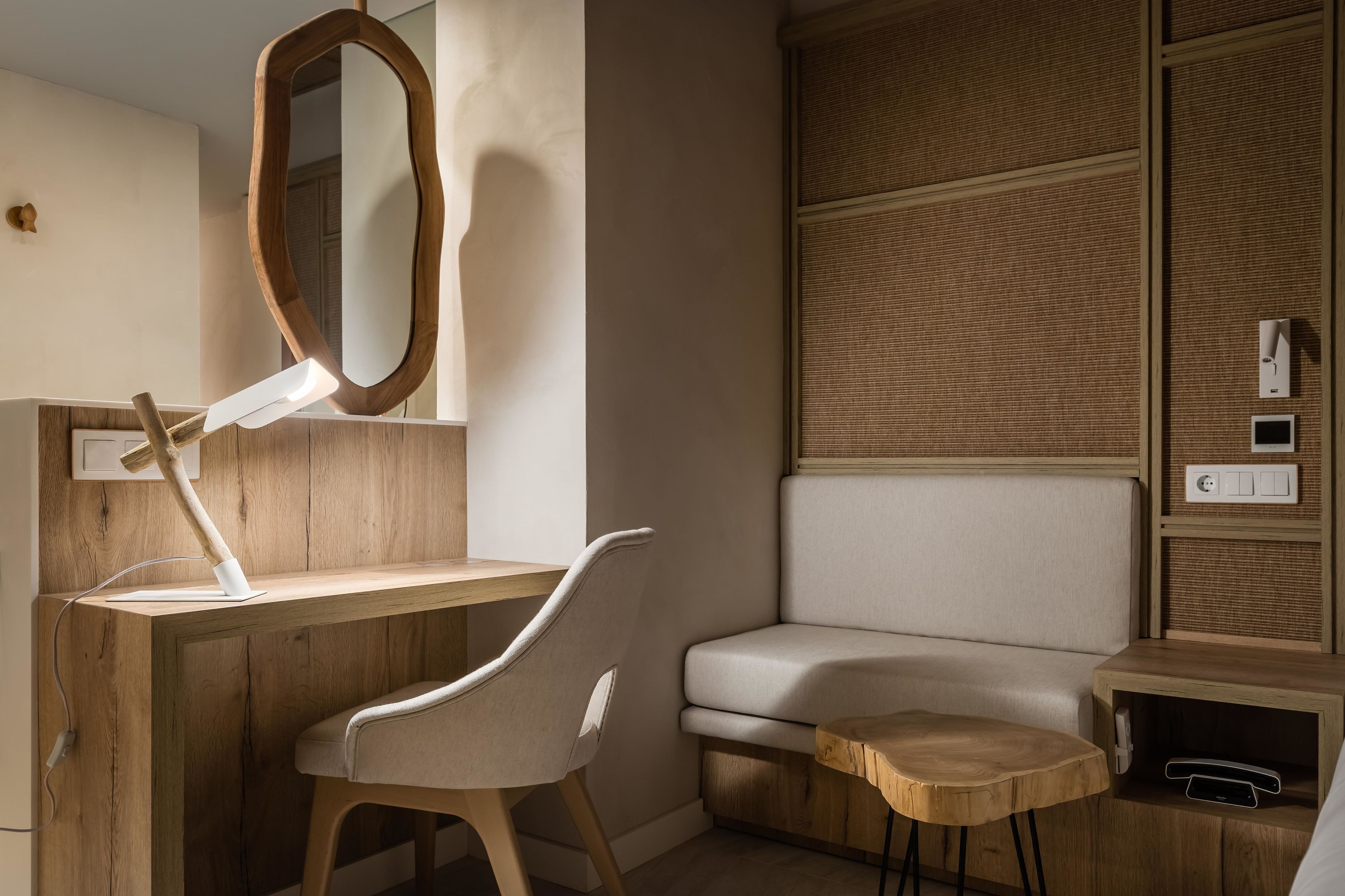A modern bathroom with a wooden vanity, a mirror, a chair, and a cushioned bench.