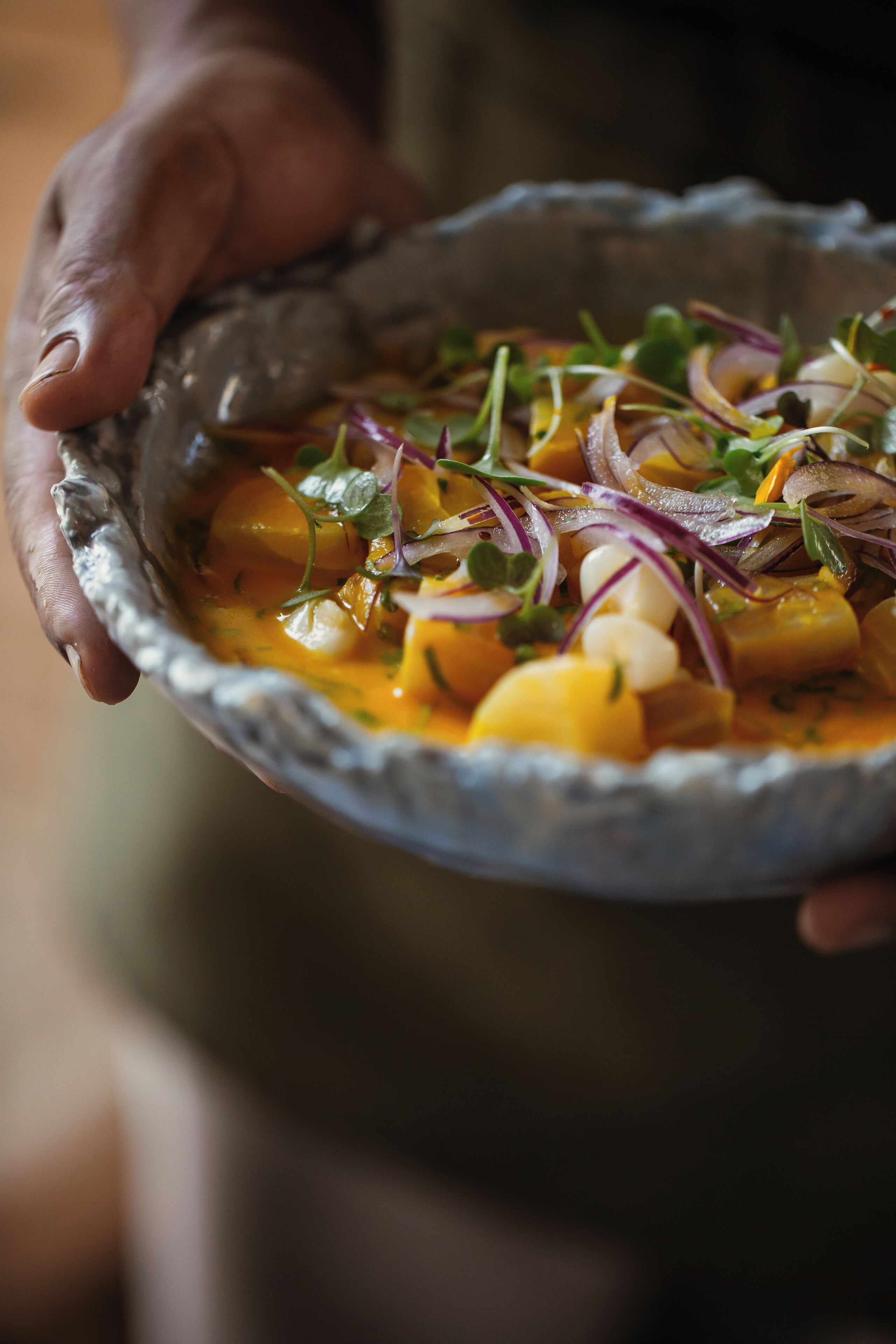 A person holding a bowl of food with various ingredients.