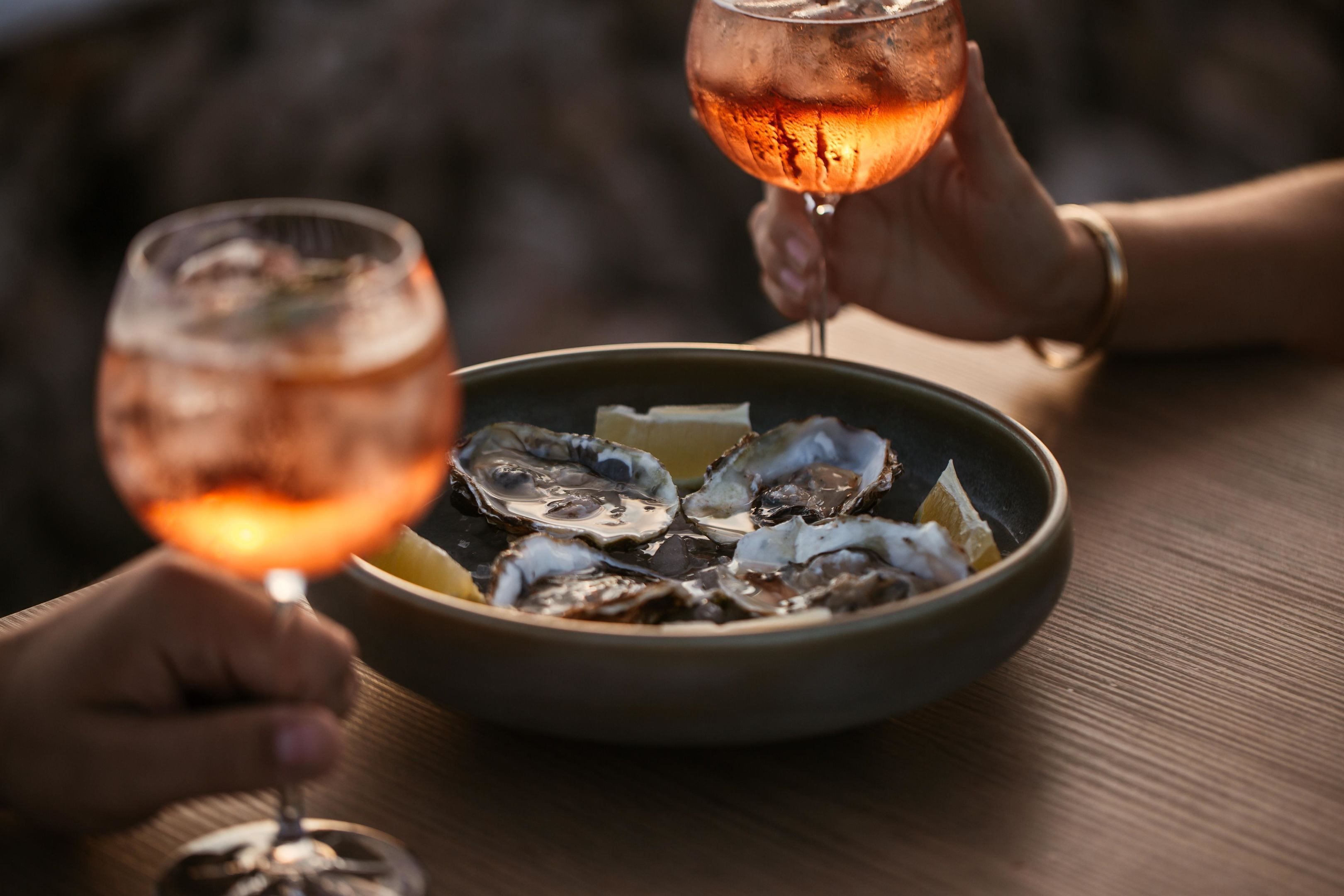 A bowl of oysters with lemon wedges on a table.