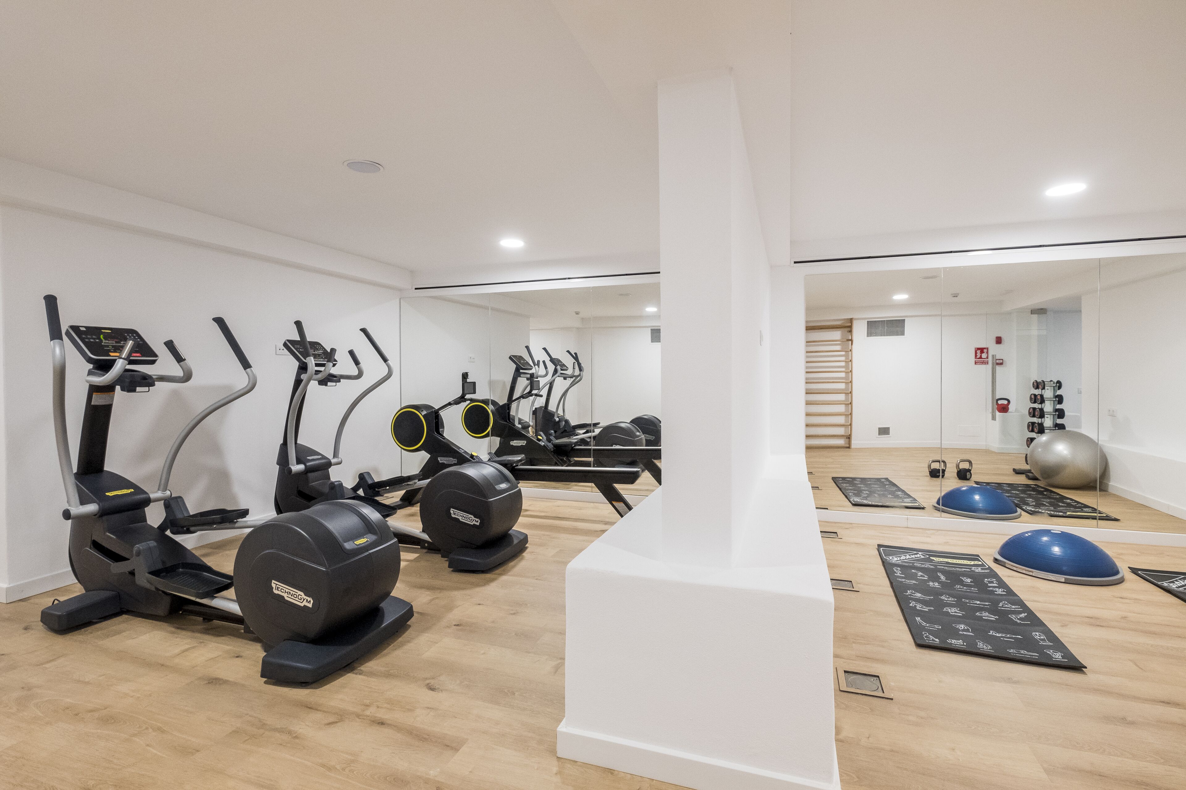 A modern gym with various exercise equipment including treadmills, elliptical machines, and free weights.