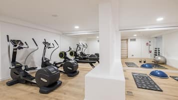 Een moderne fitnessruimte met diverse trainingsapparaten, waaronder loopbanden, elliptische trainers en losse gewichten.
