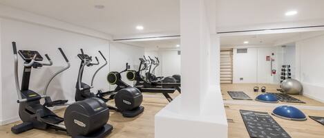 A modern gym with various exercise equipment including treadmills, elliptical machines, and free weights.