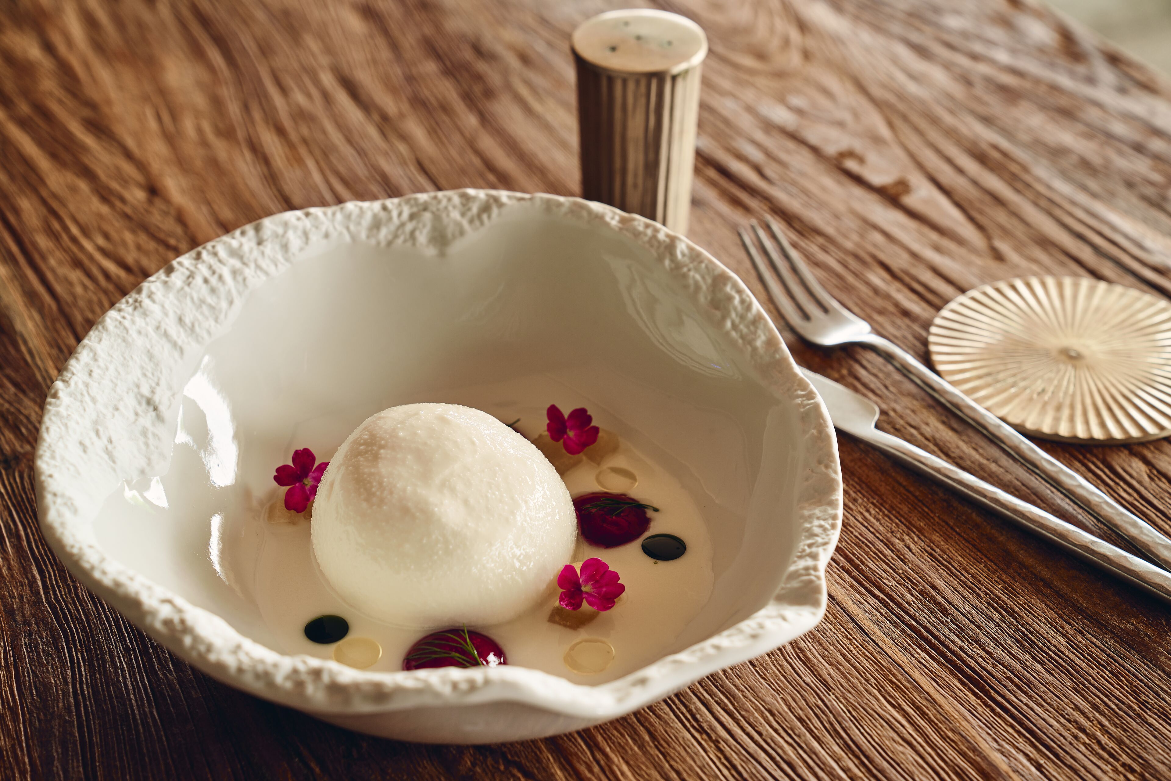 Un bol en céramique blanche contenant un dessert, posé sur une table en bois.