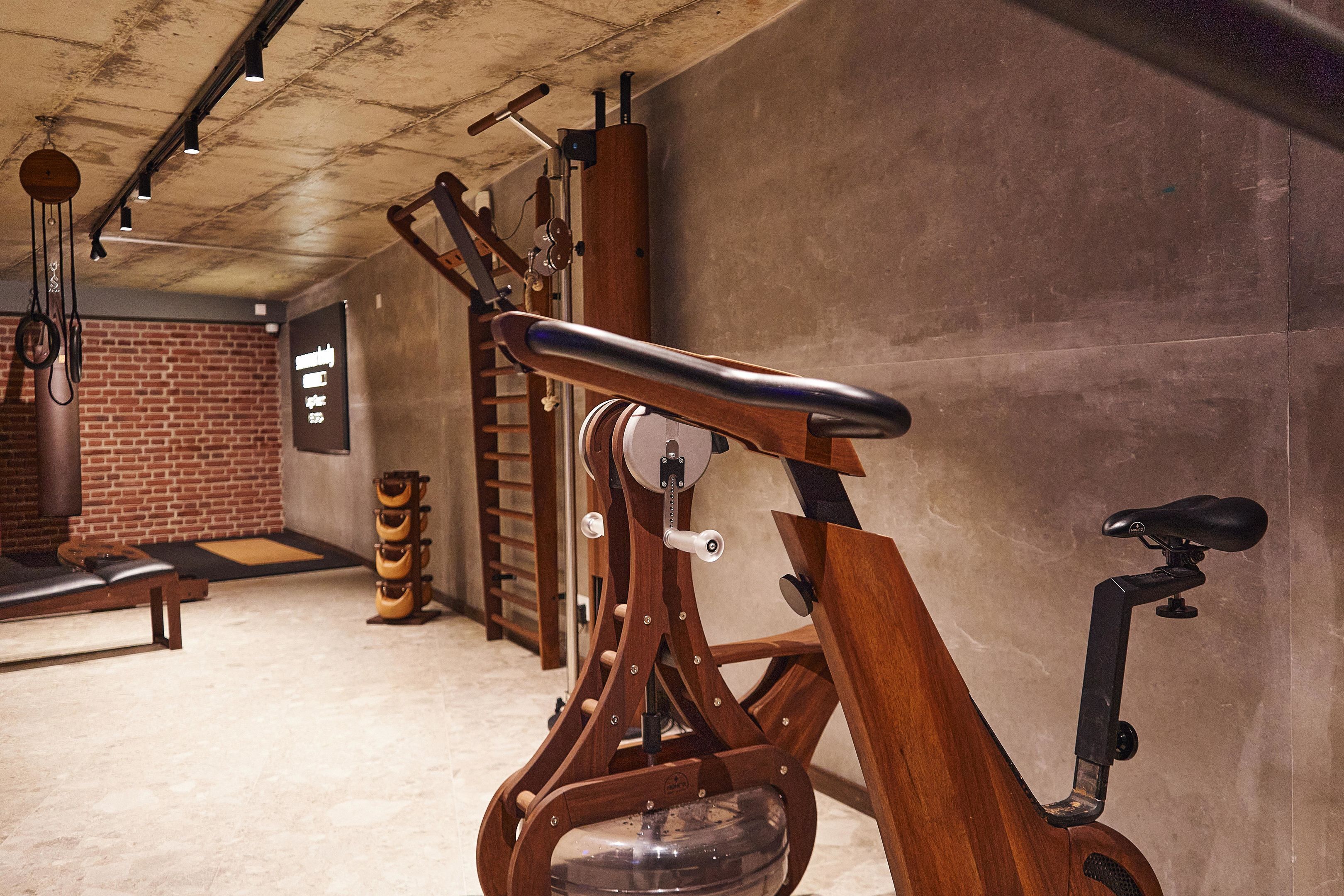 A stationary bike in a room with a brick wall and a concrete floor.