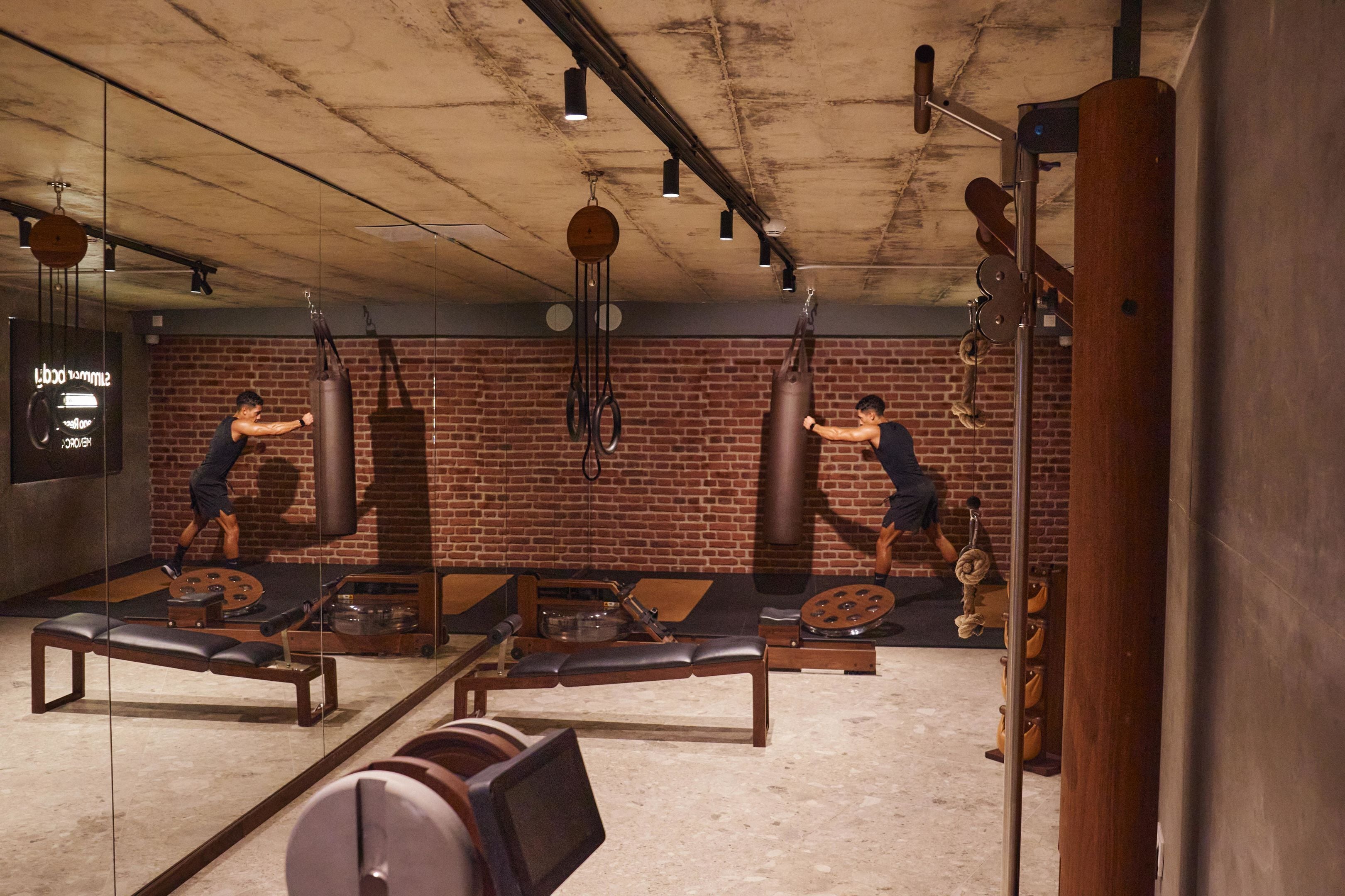 Un gimnasio con paredes de ladrillo, bancos de madera y diverso equipo de ejercicio.