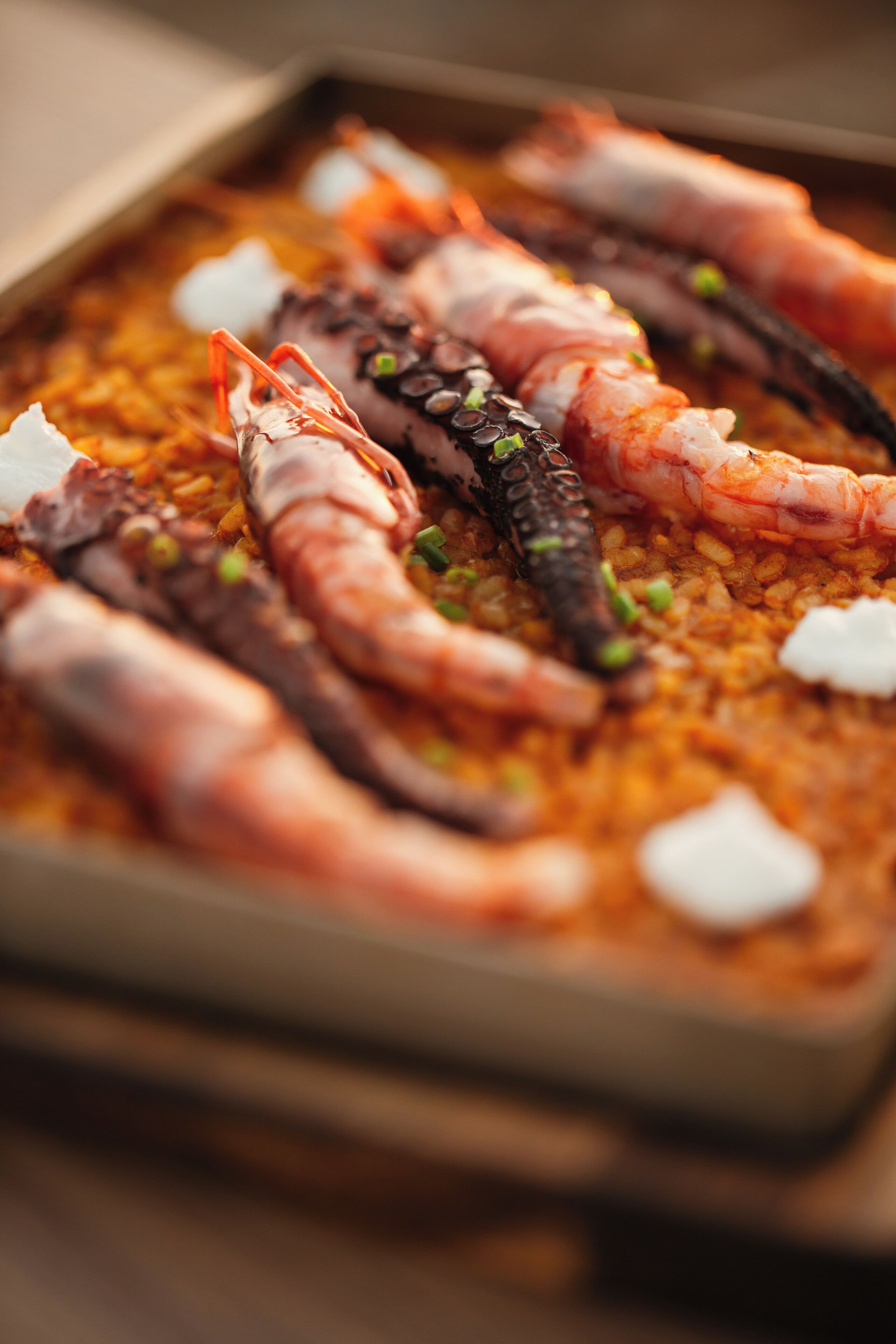 Una bandeja con mariscos, incluyendo camarones y calamares, servida sobre arroz.