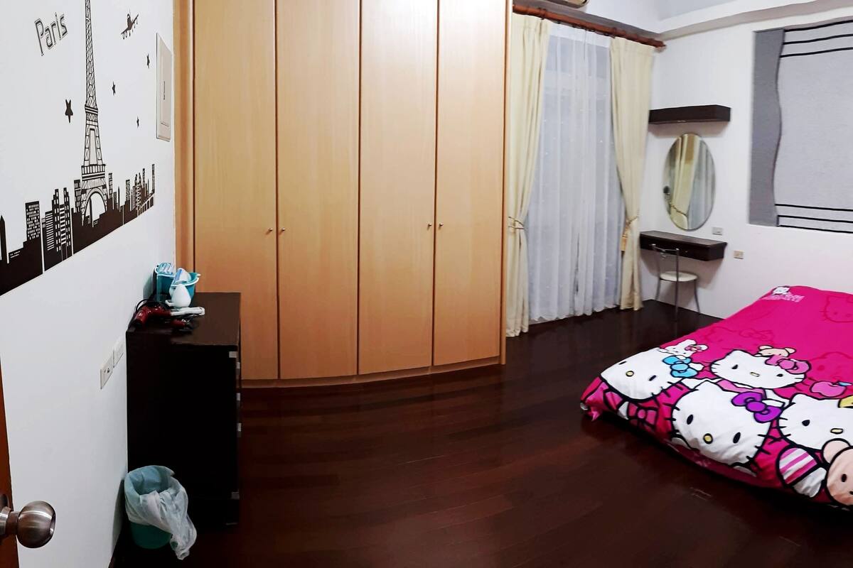 Een slaapkamer met een bed, een kast, een bureau en een spiegel.