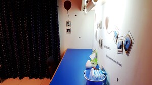 Une pièce avec une table bleue, une chaise bleue, un mur orné de motifs en forme d’étoiles et un autre mur décoré de photos et de textes.