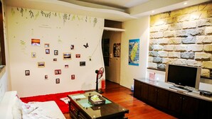 Un salon comprenant un canapé, une table basse, un téléviseur à écran plat, un mur en pierre et divers éléments de décoration murale.