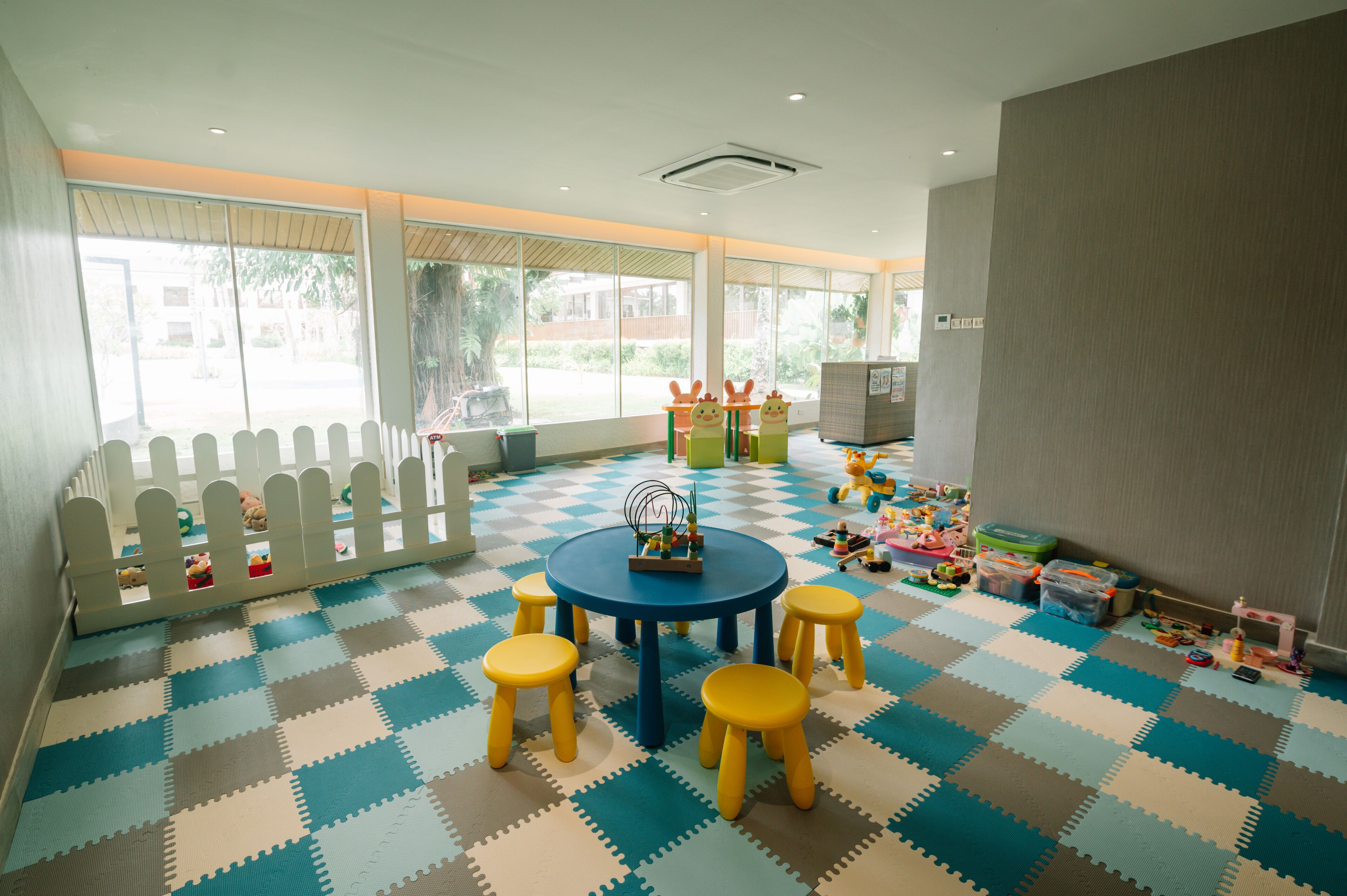 A playroom with a checkered floor, a white fence, and various toys.