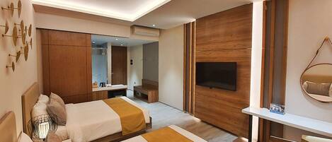Habitación de hotel con dos camas, un televisor, un escritorio y un espejo.