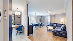 Un salon moderne avec un canapé, un coin repas comprenant une table et des chaises, et un espace cuisine équipé d’une cuisinière.