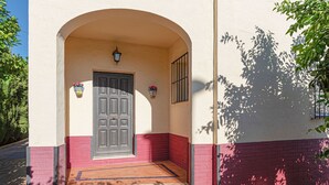 Un bâtiment avec une porte grise, un petit porche et une base en briques rouges.