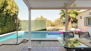 Un espace extérieur abrité avec une piscine, des chaises longues et une pergola.