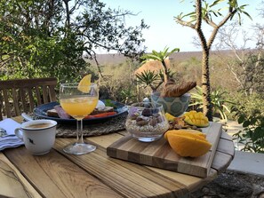 A table set with a glass of orange juice, a croissant, a bowl of almonds, a plate with toast and fruit, and a cup of coffee. - The Wild Blue Lodge SAFARI & SPA (Hoedspruit)