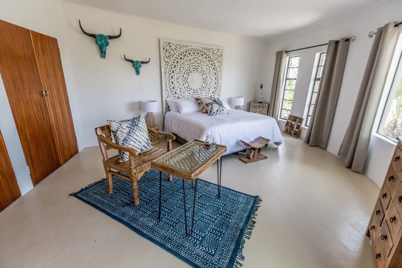 A bedroom with a bed, bedside tables, a chair, a rug, and a wooden cabinet.