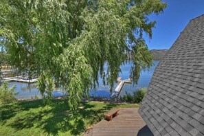 A wooden deck with a bench, overlooking a calm lake with a dock and a tree. - Storybook Lakefront: Luxury, Custom Built Lakefront Estate with Outdoor Hot Tub & Boat Dock! (Big Bear Lake)