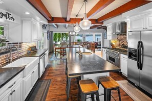 Een moderne keuken met een groot eiland, roestvrijstalen apparatuur en houten details.