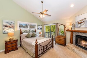 A bedroom with a bed, a ceiling fan, a fireplace, and a window with a view. - Storybook Lakefront: Luxury, Custom Built Lakefront Estate with Outdoor Hot Tub & Boat Dock! (Big Bear Lake)
