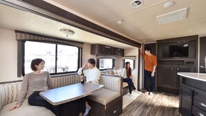 Interior acolhedor de uma motorhome, com área de refeições, assentos e cozinha.