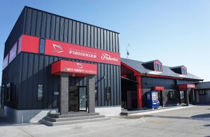 A modern building with a prominent red and black facade, featuring signage for 'Fisheries' and 'Best Amenity Marina'.