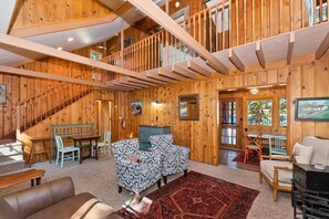 A spacious interior with a wooden staircase, a dining area, and a seating area with patterned chairs.