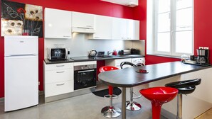 Une cuisine moderne avec des meubles blancs, un plan de travail noir et des tabourets de bar rouges.