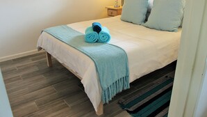 A neatly made bed with a blue towel, a matching blue throw blanket, and two matching pillows. - Bell Rock 19 (Plettenberg Bay)