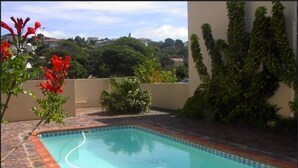 A rectangular swimming pool with a tiled edge, surrounded by a brick patio. - Bell Rock 19 (Plettenberg Bay)