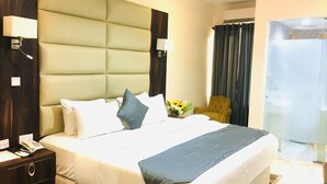 A hotel room with a large bed, bedside lamps, a telephone, a nightstand, and a chair.