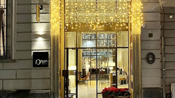 A hotel entrance with a glass door, decorative lights, and a signboard.