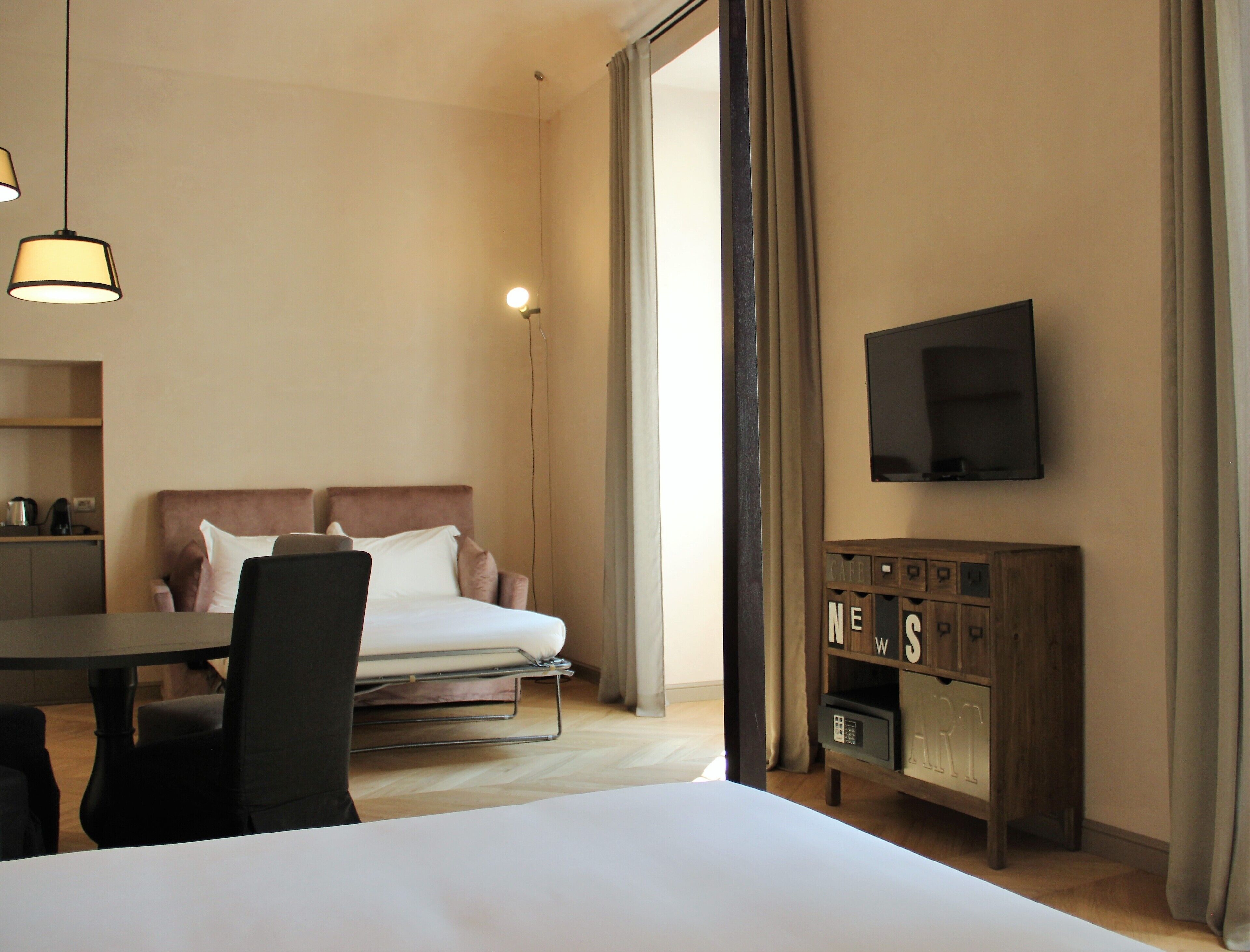A hotel room with a bed, a desk, a chair, a TV, and a cabinet.