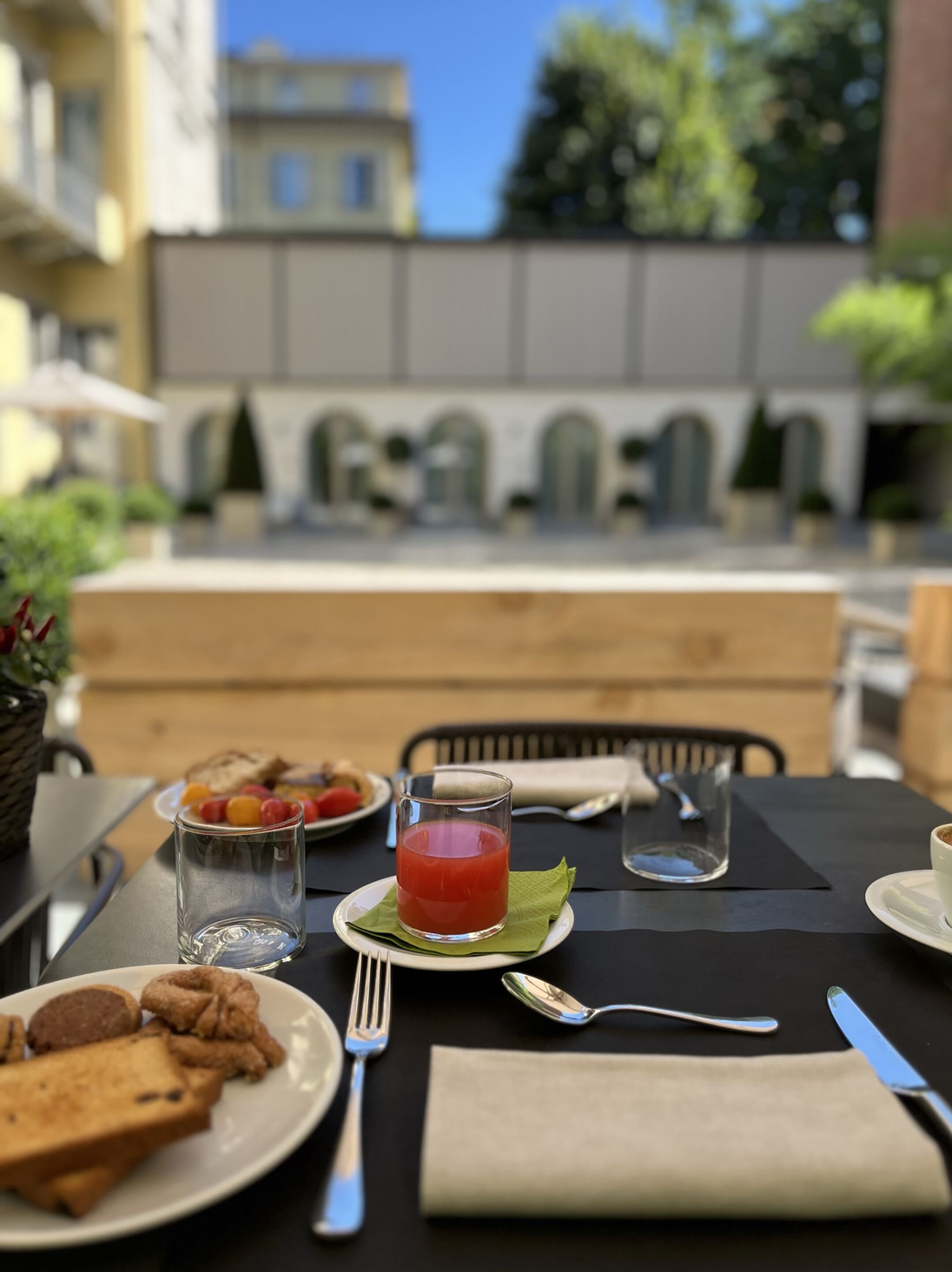 Zona pranzo all'aperto con tavolo apparecchiato per la colazione, inclusi toast, frutta e un bicchiere di succo.