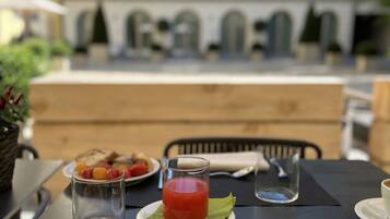 Zona pranzo all'aperto con tavolo apparecchiato per la colazione, inclusi toast, frutta e un bicchiere di succo.