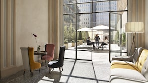 A spacious room with a large window, a sofa, a chair, and a table.