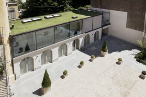 A building with a flat roof, large windows, and a courtyard with potted plants.