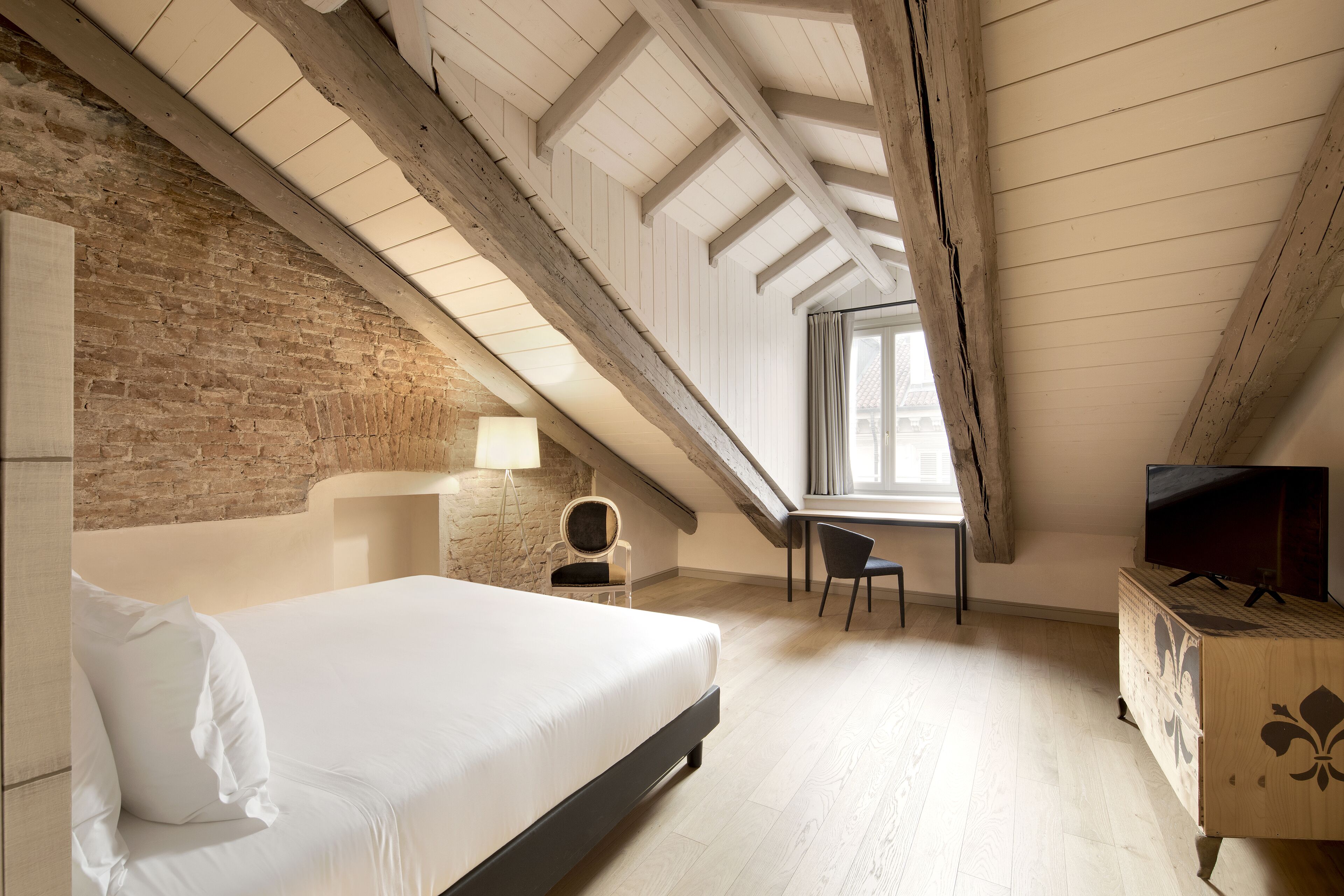 A bedroom with a large bed, a desk, and a TV.