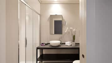 Un baño moderno con cabina de ducha de vidrio, un lavabo blanco y un espejo sobre él.
