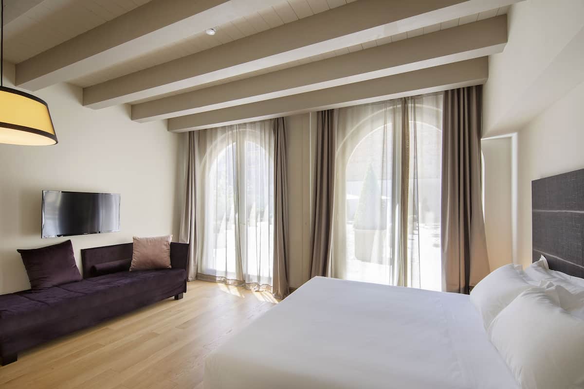 Et moderne hotelværelse med en stor seng, en sofa og et fjernsyn på væggen.