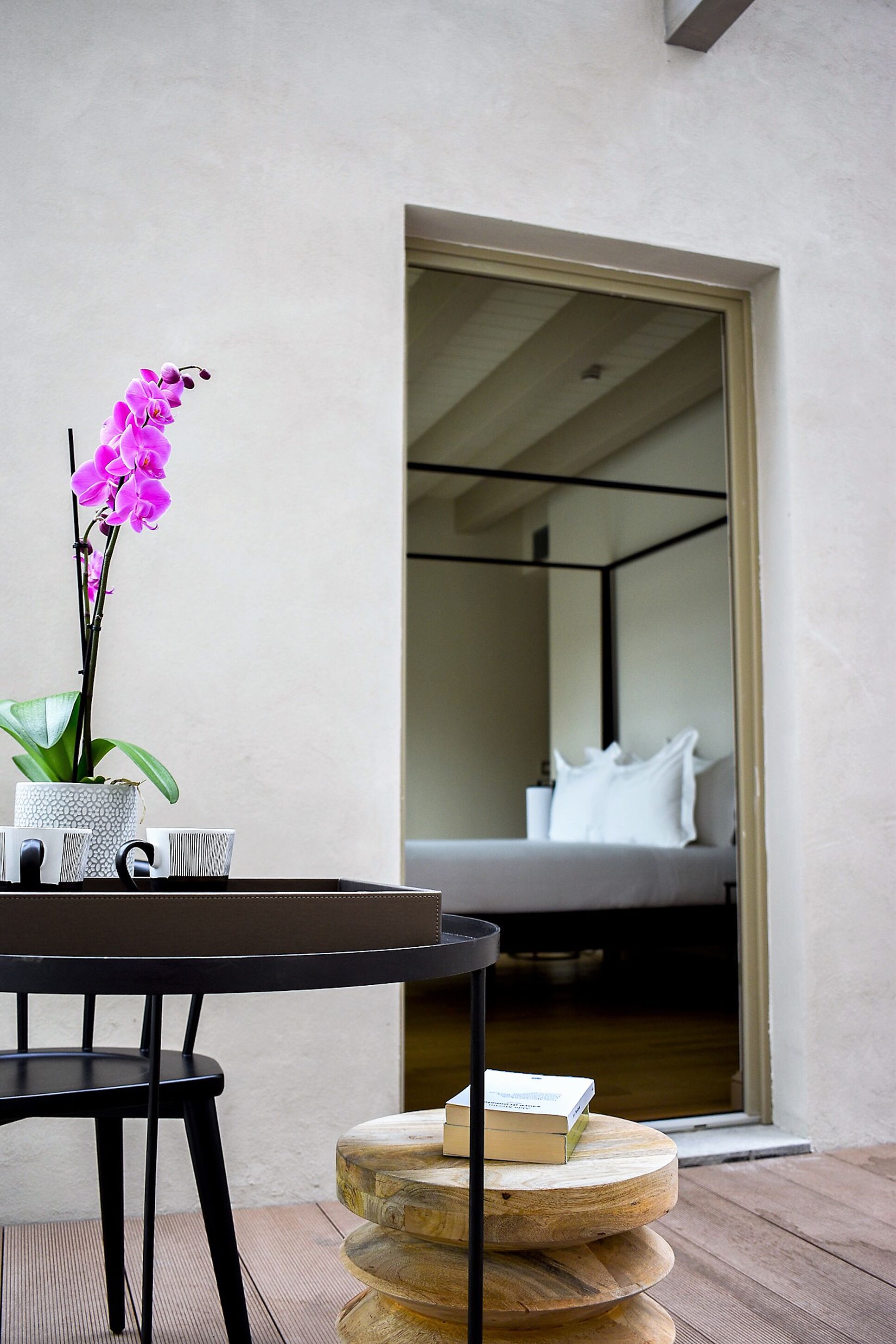A modern room with a bed, a small table with a book, and a potted orchid.