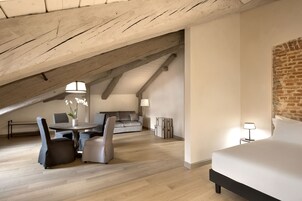 Un dormitorio tipo loft moderno con techo inclinado, una cama, una mesa de comedor con sillas y un sofá.