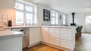 Eine moderne Küche mit weißen Schränken, einem eingebauten Geschirrspüler und einer großen Kochinsel mit Barhocker.