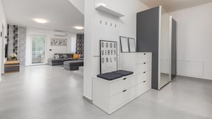 Een moderne woonkamer met een grijze bank, een wit kastje met lades en een grote spiegel.