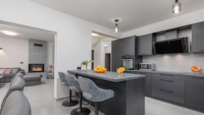 Een moderne keuken met een centraal eiland, barkrukken, een flatscreen-tv en een magnetron.