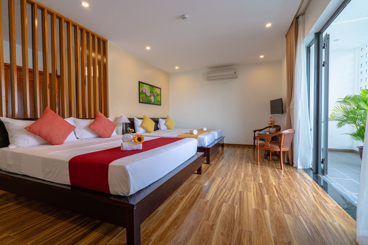 A hotel room with a large bed, a desk, and a chair. There is a window with a view of a building.