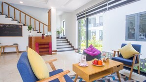 A modern hotel lobby with a staircase, seating area, and a view of the outdoors. - Golden Star Villa Hoi An (Da Nang)