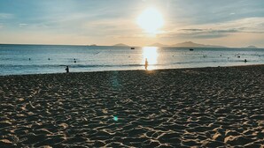A beach with a clear sky and the sun setting over the water. - Golden Star Villa Hoi An (Da Nang)