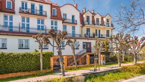 A row of multi-story residential buildings with balconies, a gated entrance, and a pathway.