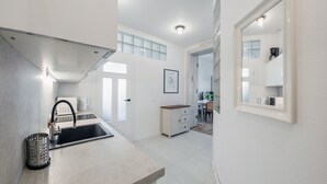 A modern kitchen with a sink, a coffee machine, and a dining area with a table and chairs.