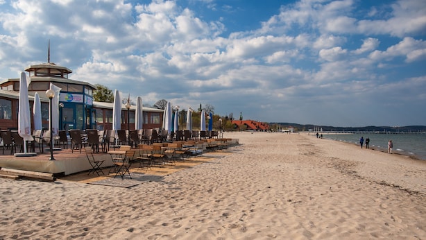 A beachside restaurant with outdoor seating and a view of the sea.